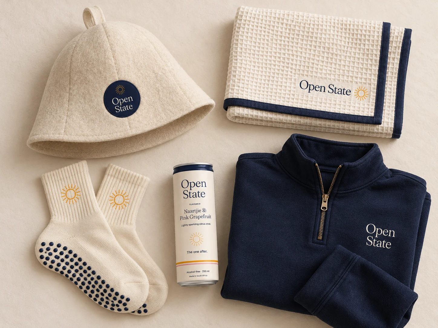 Open State capsule concept: cream sauna hat, waffle towel and grip socks, navy warm-up layer and cream can
